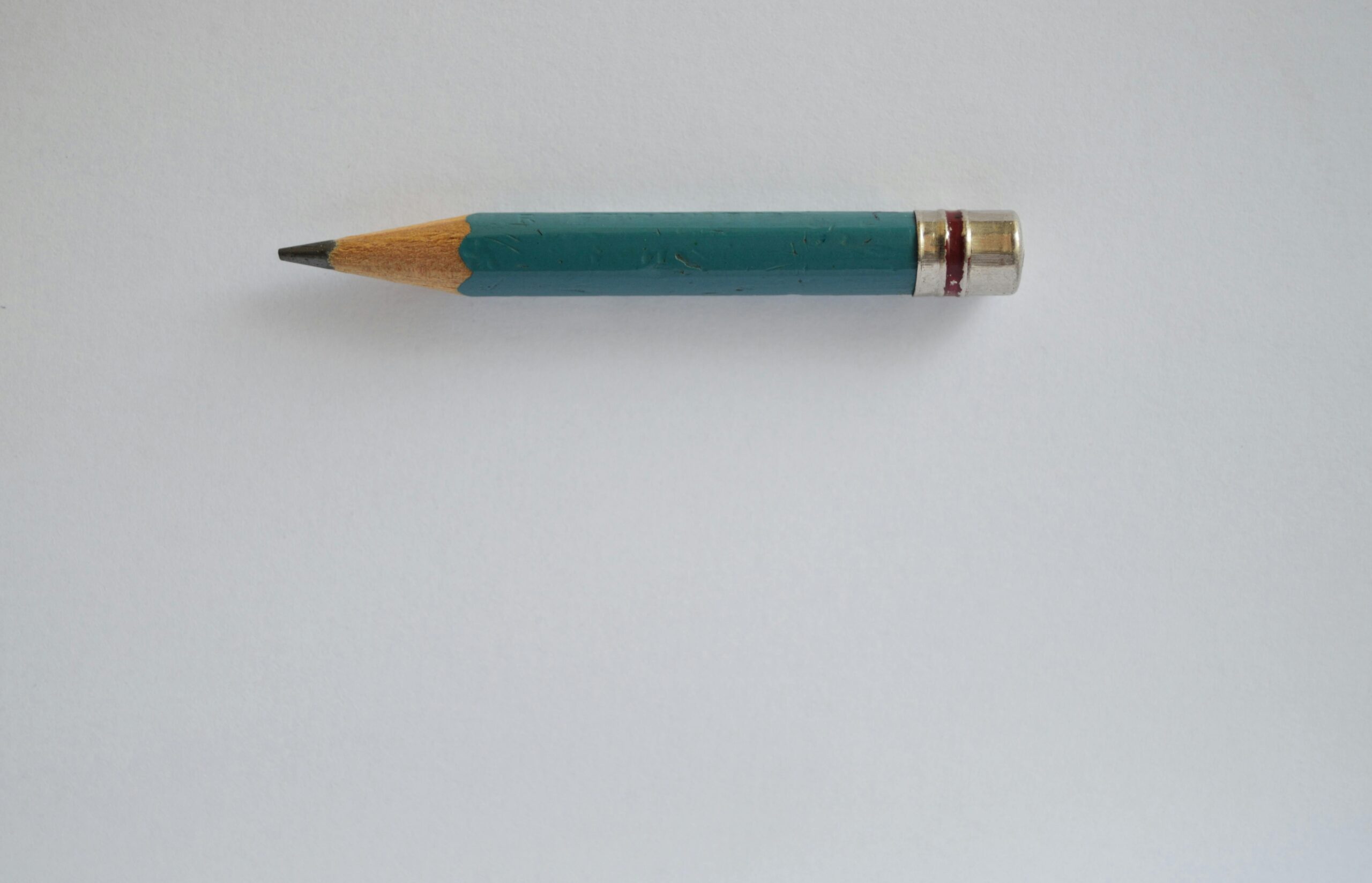 Minimalist image of a sharpened green pencil on a plain white background.